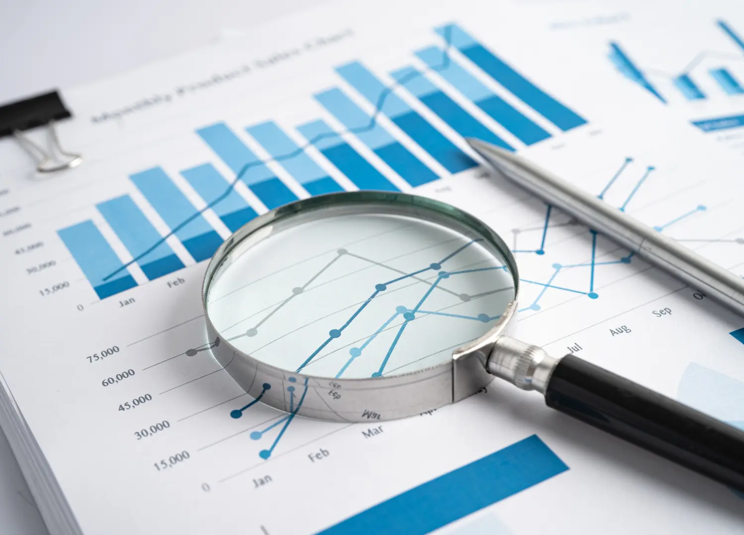 Grafico di analisi dei dati con una lente d'ingrandimento e una penna, che evidenzia dettagli di statistiche e tendenze, rappresentando l'importanza della ricerca e dell'analisi nelle strategie di marketing